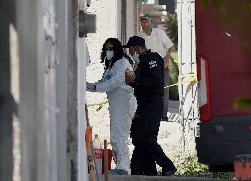 A forensics worker and a policeman enter the house of alleged serial killer ‘Andres’ in Mexico state. Photo: AFP