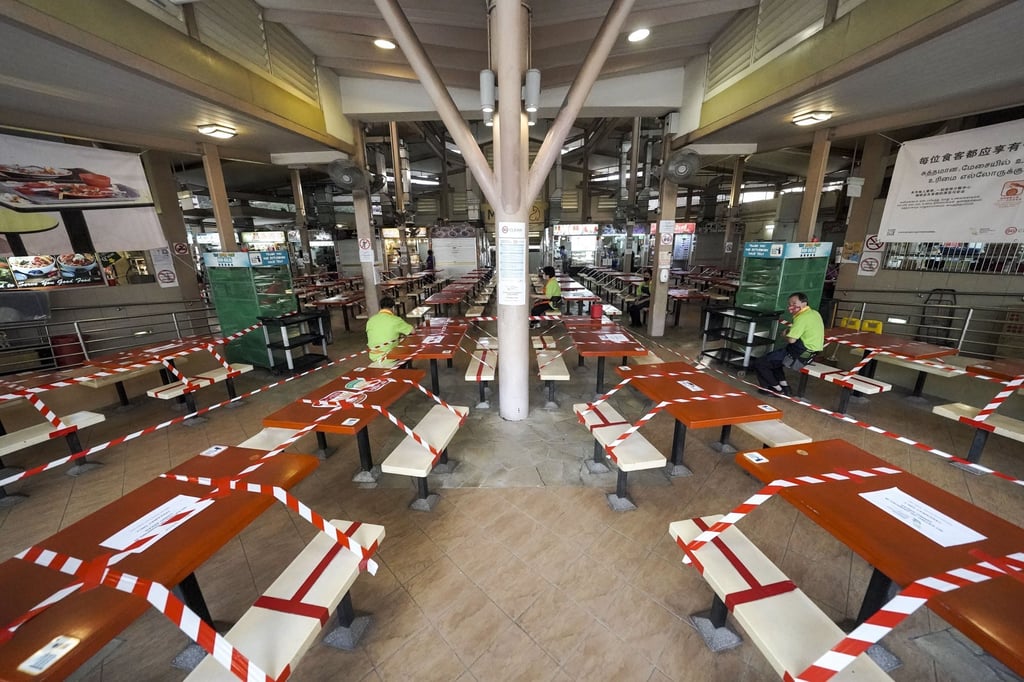 Tables are cordoned off at a hawker centre in Singapore, which in May tightened Covid-19 restrictions following a rise in cases. Photo: EPA Tables are cordoned off at a hawker centre in Singapore, which in May tightened Covid-19 restrictions following a rise in cases. Photo: EPA