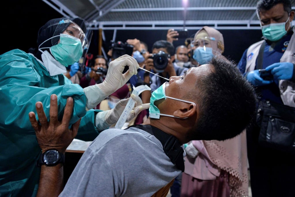 A health worker takes a swab sample from a man to check for Covid-19 at a coffee shop in Banda Aceh, Indonesia. The coronavirus has hit the Indonesian economy hard. Photo: AFP