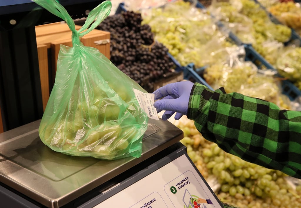 A customer weighs grapes at a supermarket. Bring your own bag when grocery shopping to cut down on your use of plastic bags. Photo: Getty Images