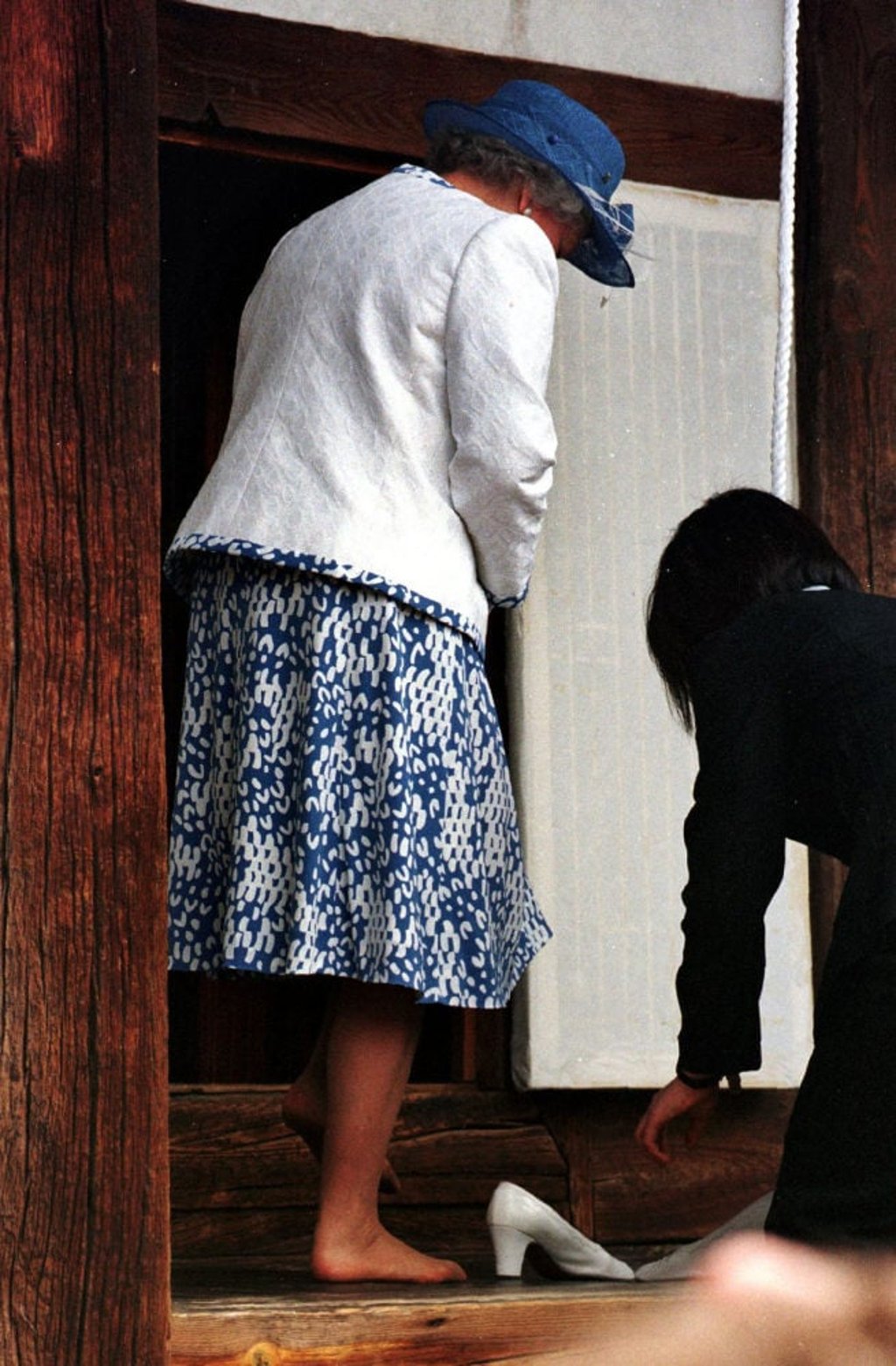 Queen Elizabeth removes her shoes at the request of members of a Korean family on a visit to their 400-year-old house in Hahoe. Photo: AP