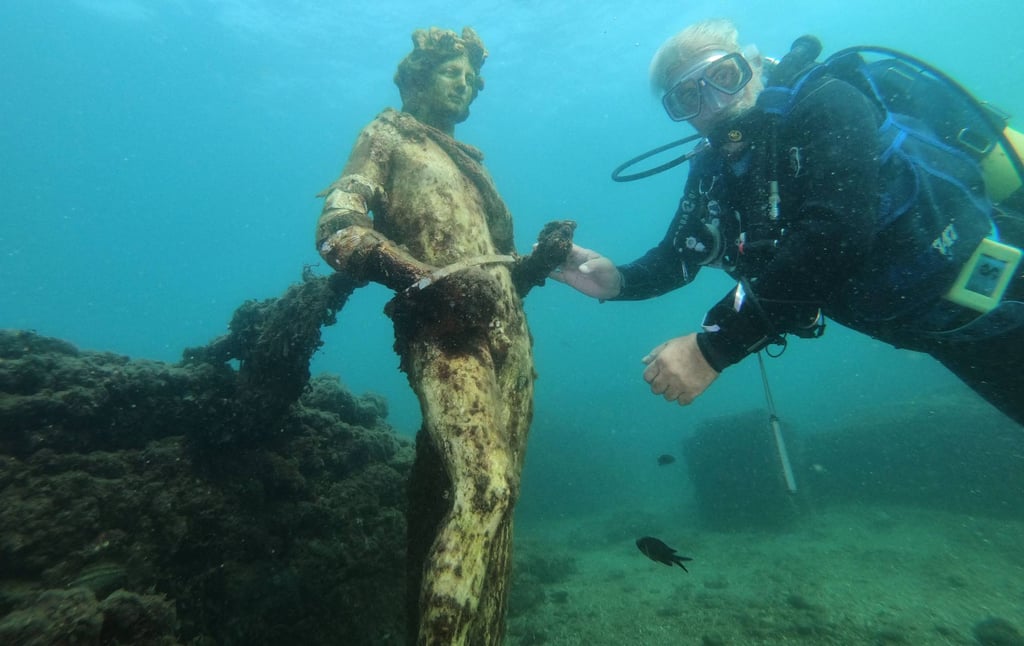 A diver touches a replica statue of Dionysus at the Baiae Underwater Park in Naples. Photo: AFP