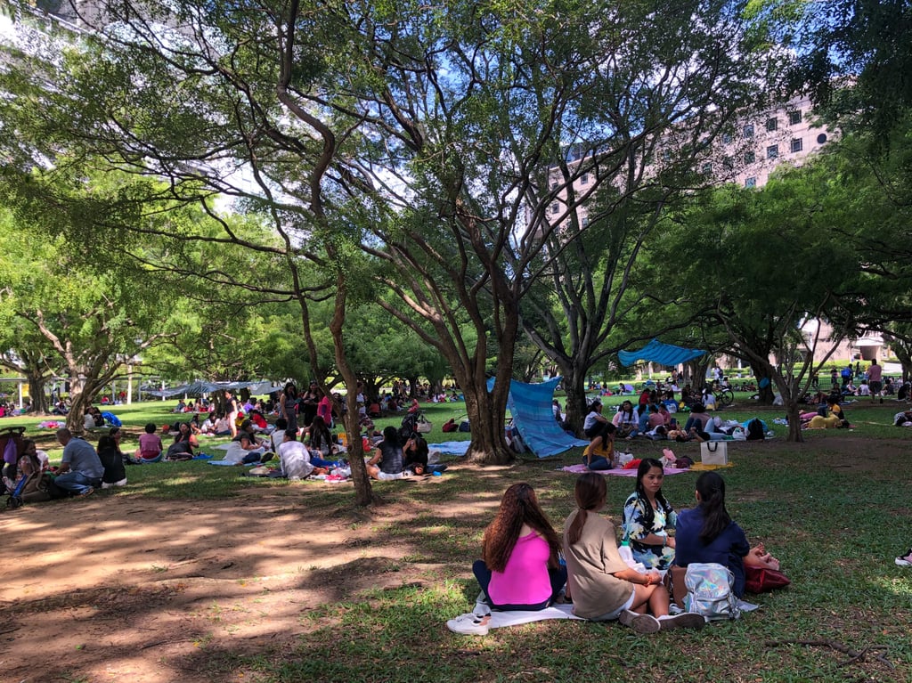 Domestic workers gather on a grass patch behind Somerset MRT Station in Singapore.