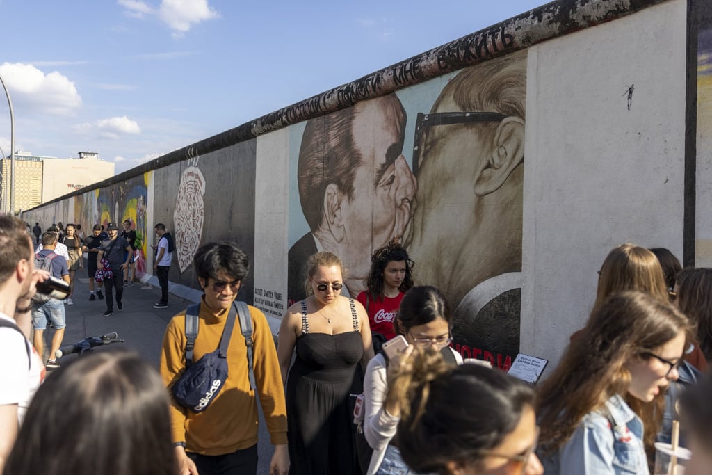 Visitors walk past a mural showing former Soviet leader Leonid Brezhnev kissing ex-East German President Erich Honecker at the East Side Gallery in Berlin. Photo: Getty Images