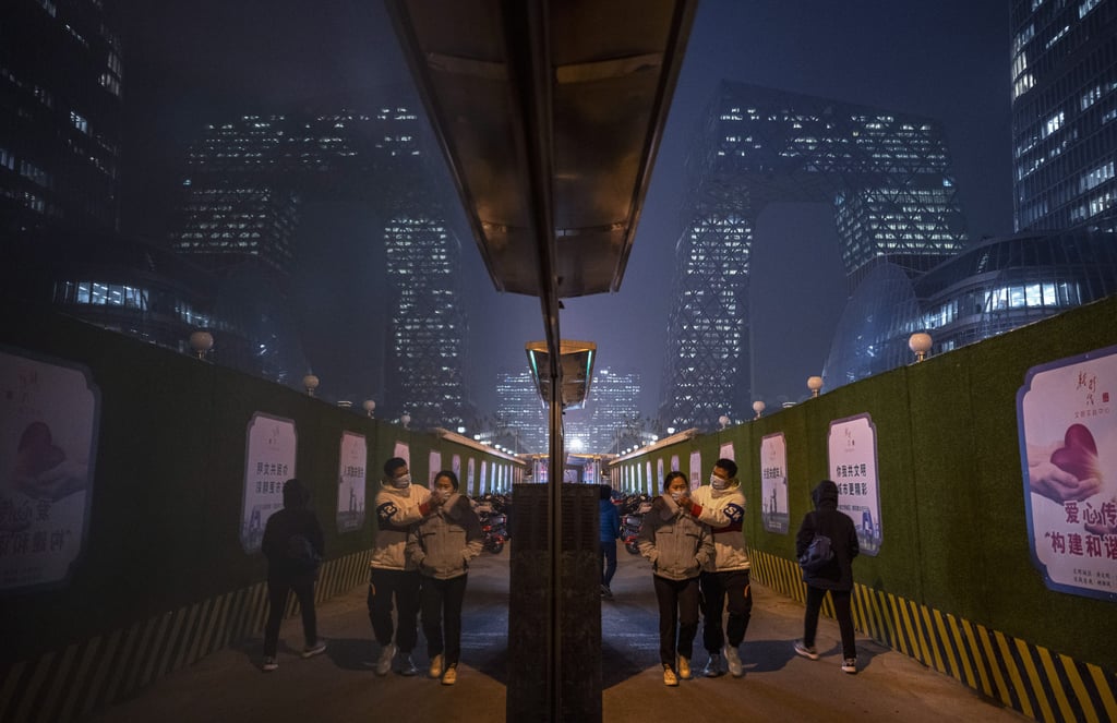 A man adjusts the face mask on a woman as they walk in Beijing. Photo: Getty Images