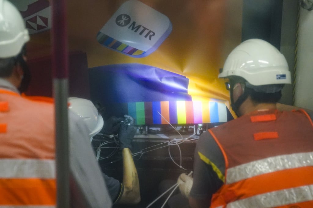 MTR Corp workers examine a billboard believed to have clipped the doors on a passing train. Photo: Sam Tsang MTR Corp workers examine a billboard believed to have clipped the doors on a passing train. Photo: Sam Tsang
