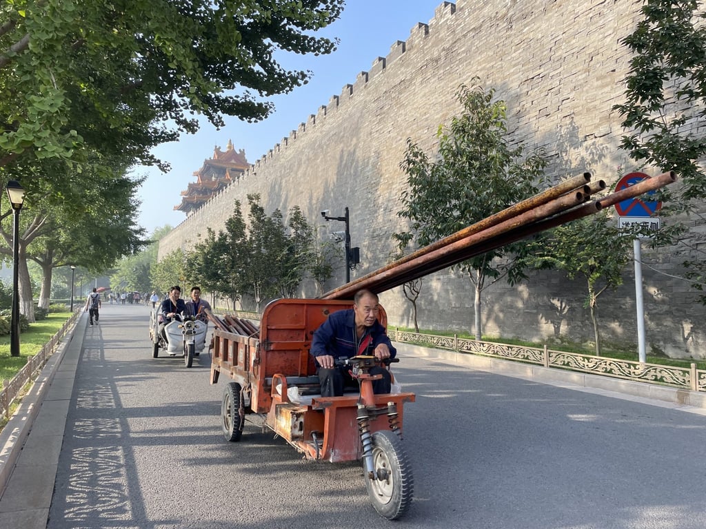 A migrant worker rides a tricycle carrying iron and steel poles for construction outside the Forbidden City, also known as the Palace Museum, in Beijing. Photo: Simon Song A migrant worker rides a tricycle carrying iron and steel poles for construction outside the Forbidden City, also known as the Palace Museum, in Beijing. Photo: Simon Song