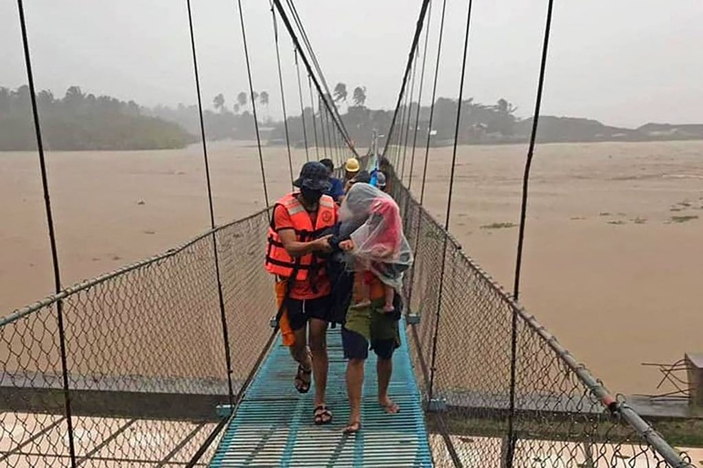 Philippine coastguard members evacuate residents across a bridge in Tubay town on southern Mindanao island. Photo: AFP Philippine coastguard members evacuate residents across a bridge in Tubay town on southern Mindanao island. Photo: AFP