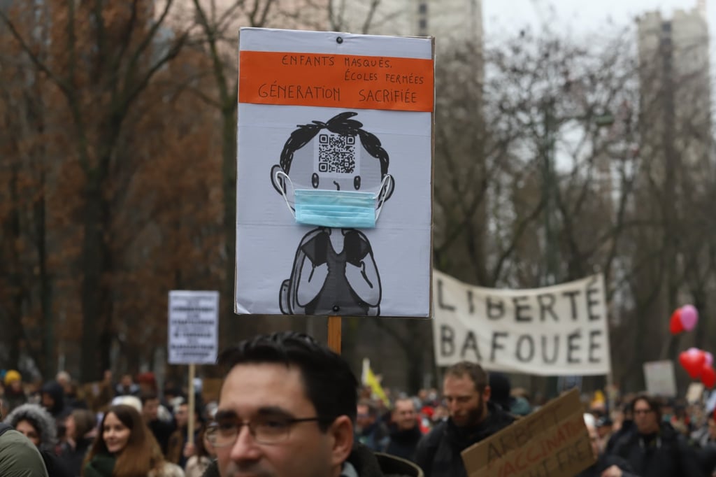 Demonstrators carry a placard depicting a child wearing a mask during a protest against Covid-19 restrictions in Belgium on December 19. The omicron mutation has added an extra layer of uncertainty, but Europe’s immediate problem is grappling with the wave of infections that has already put countries back into lockdown. Photo: Bloomberg