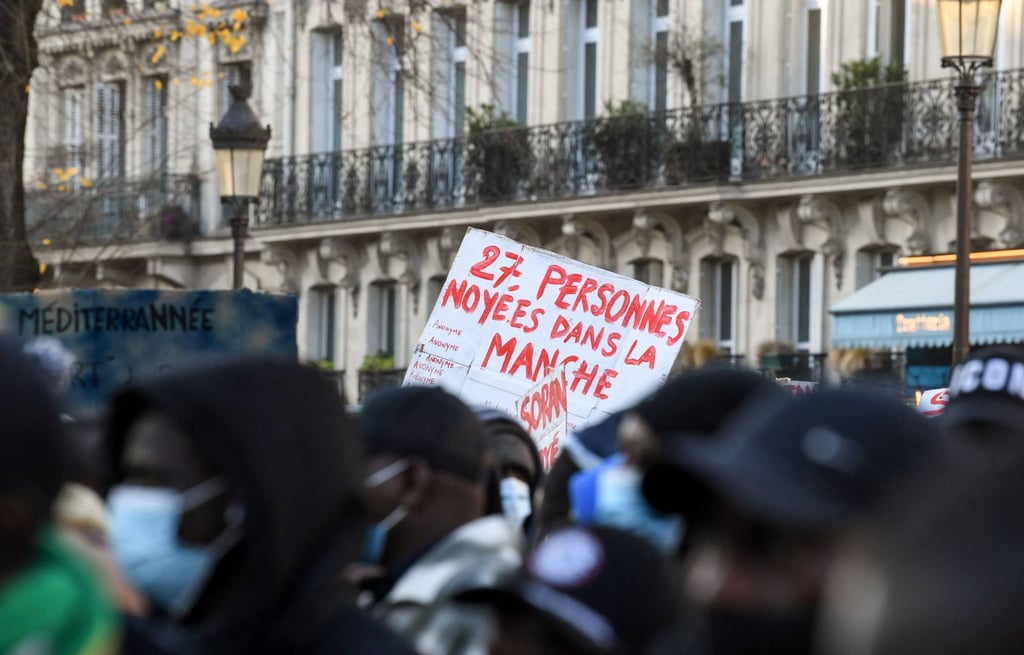 A Paris protester holds a banner reading ‘27 people drowned in the Channel” during a demonstration in favour of the regularisation of illegal migrants and their living conditions as part of a “anti-racism and solidarity” campaign on International Migrants Day on December 18, 2021. Photo: AFP