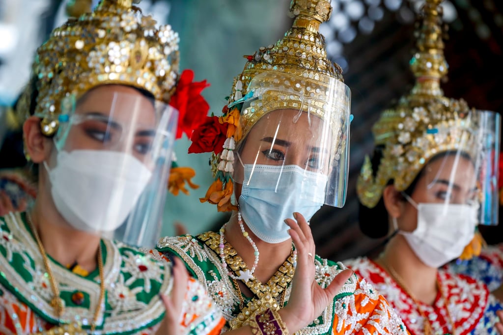 Thai dancers in face masks and shields during a performance at the nearly empty tourist spot of Erawan Shrine in Bangkok on December 21. The nation has halted quarantine-free entry to the country. Photo: EPA-EFE