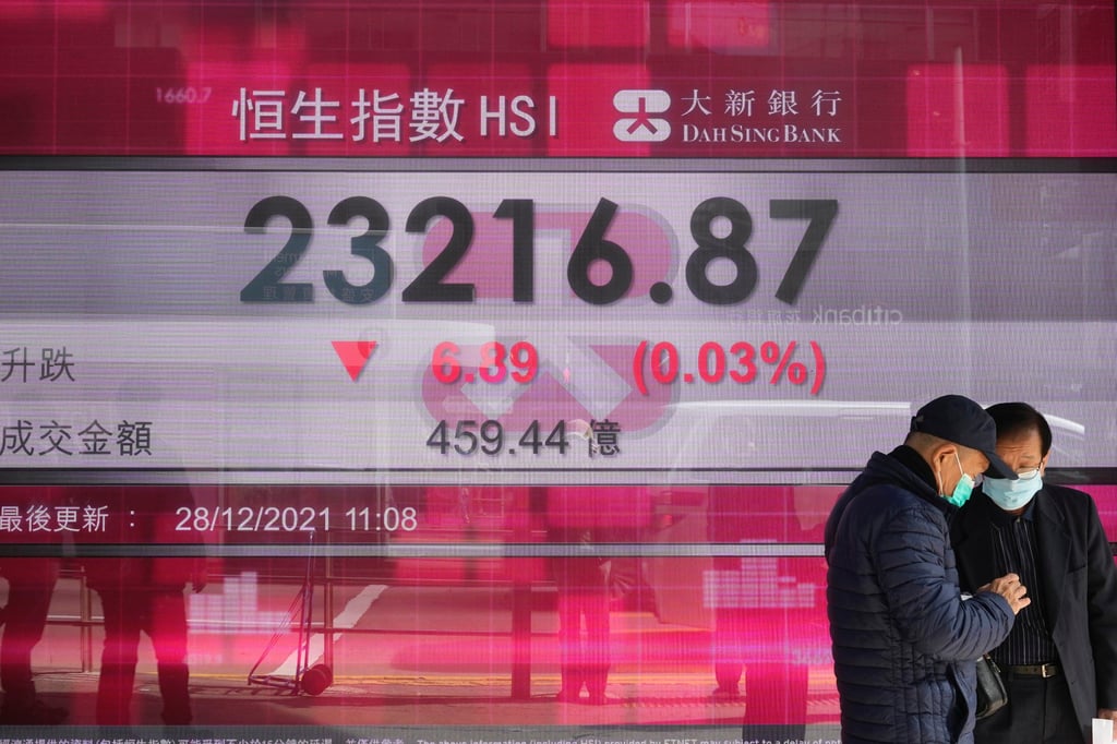 People walk past a bank’s electronic board showing the share index of the Hong Kong stock exchange on December 28, 2021. Photo: AP People walk past a bank’s electronic board showing the share index of the Hong Kong stock exchange on December 28, 2021. Photo: AP