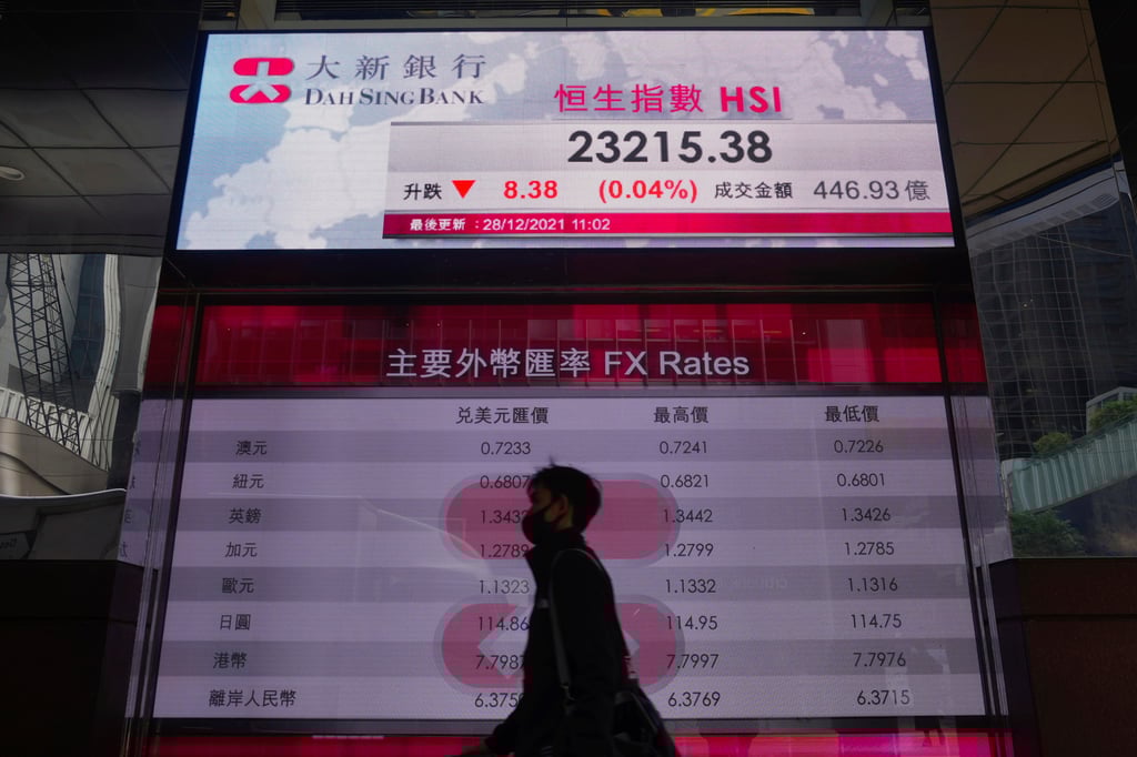 A man walks past a bank’s electronic board showing the local share index at the Hong Kong stock exchange on December 28, 2021. Photo: AP