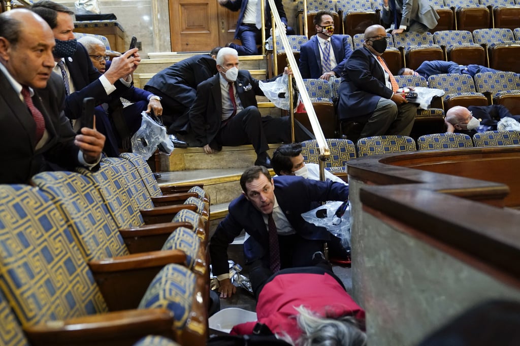 Members of Congress shelter in the House gallery as Trump supporters try to break into the House Chamber at the US Capitol on January 6, 2021. Photo: AP Members of Congress shelter in the House gallery as Trump supporters try to break into the House Chamber at the US Capitol on January 6, 2021. Photo: AP