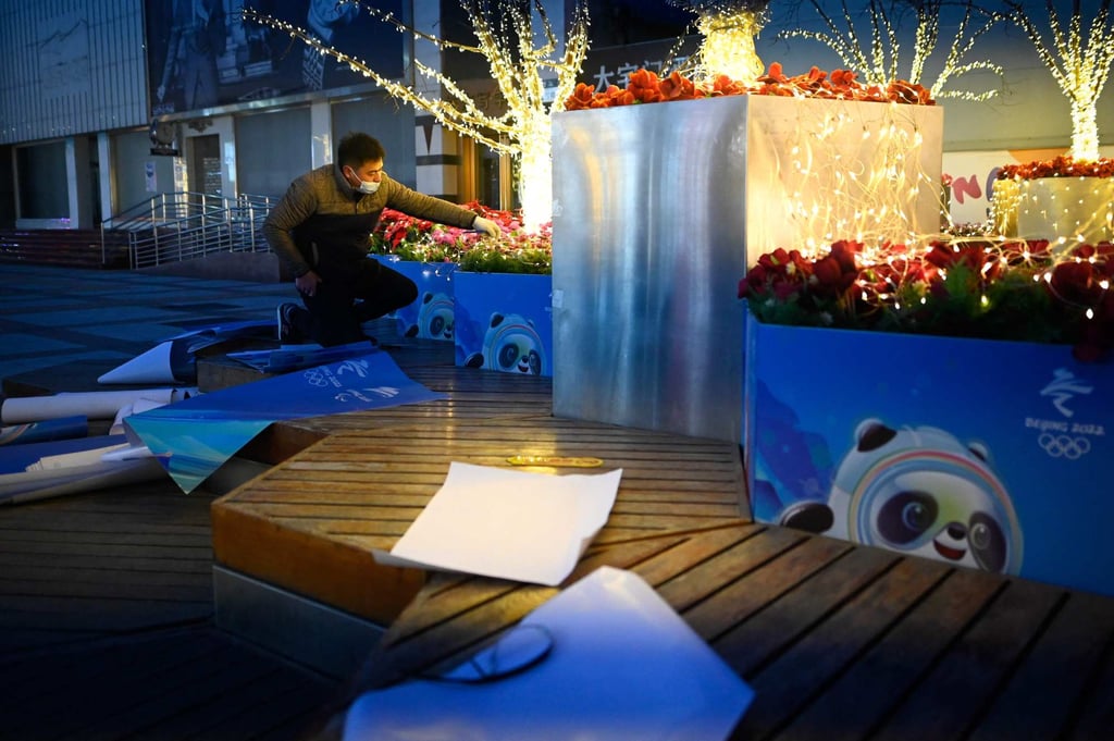 A worker sticks a poster for the 2022 Winter Olympics on a flower bed along a busy street in Beijing. Photo: AFP A worker sticks a poster for the 2022 Winter Olympics on a flower bed along a busy street in Beijing. Photo: AFP