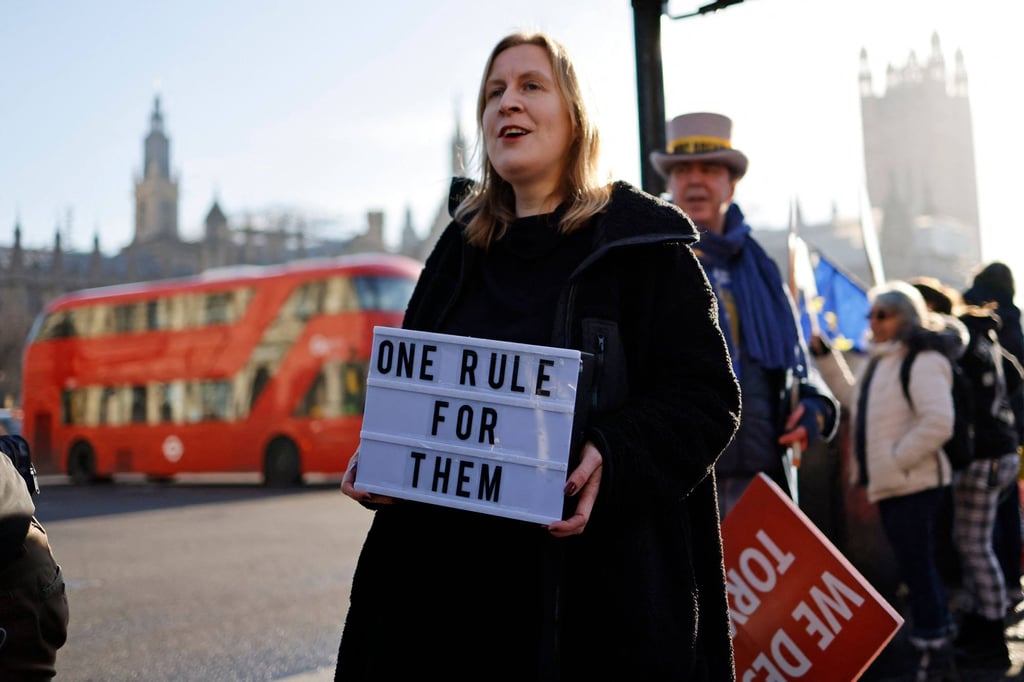 Demonstrators hold placards near the House of Commons, where Britain’s Prime Minister was apologising. Photo: AFP Demonstrators hold placards near the House of Commons, where Britain’s Prime Minister was apologising. Photo: AFP