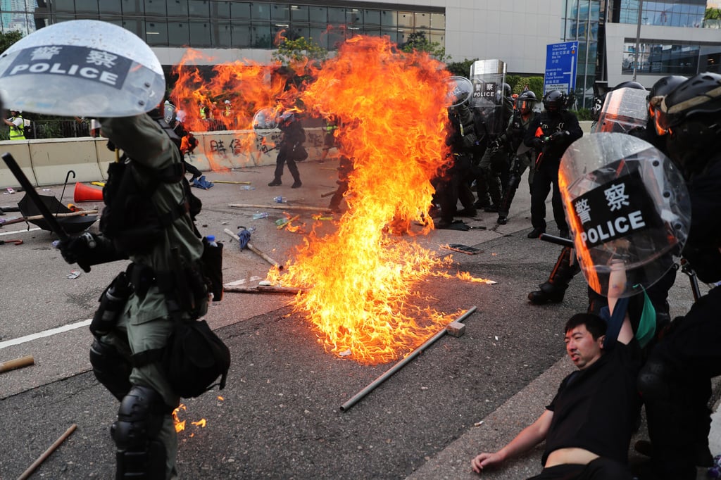 A petrol bomb lands near riot police, close to the Ngau Tau Kok Police Station, while police officers arrest protesters in August 2019. Photo: CWH