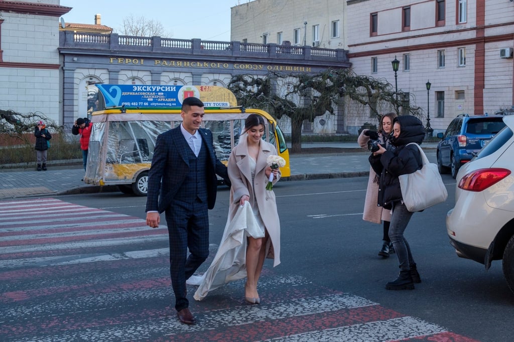 Pedestrians take photographs of a just-married couple crossing a road in Odessa, Ukraine. President Vladimir Putin has repeatedly said he currently has no plans to attack the country. Photo: Bloomberg