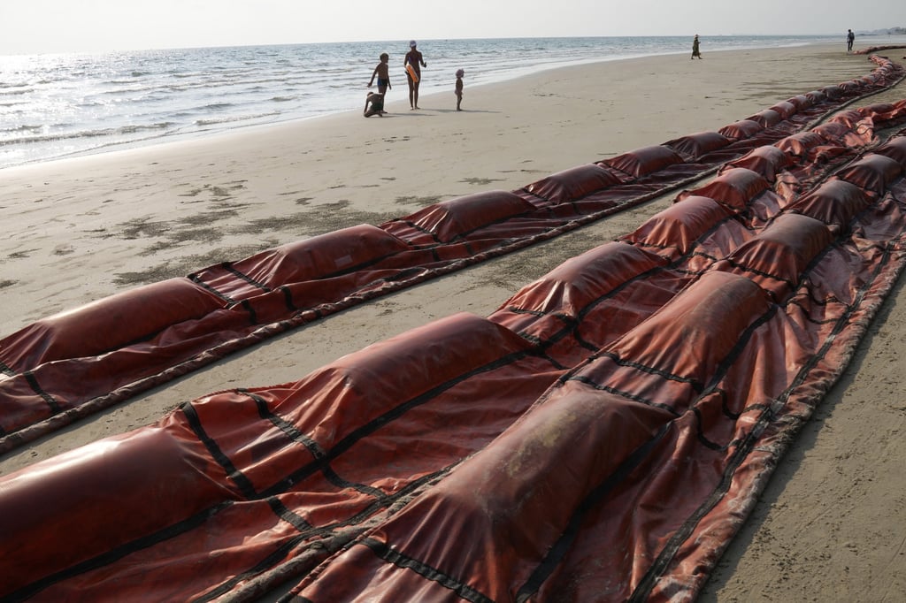 Tourists on a beach near oil spill booms laid out to try and contain any oil approaching from a recent leak off the coast. Photo: AP Tourists on a beach near oil spill booms laid out to try and contain any oil approaching from a recent leak off the coast. Photo: AP