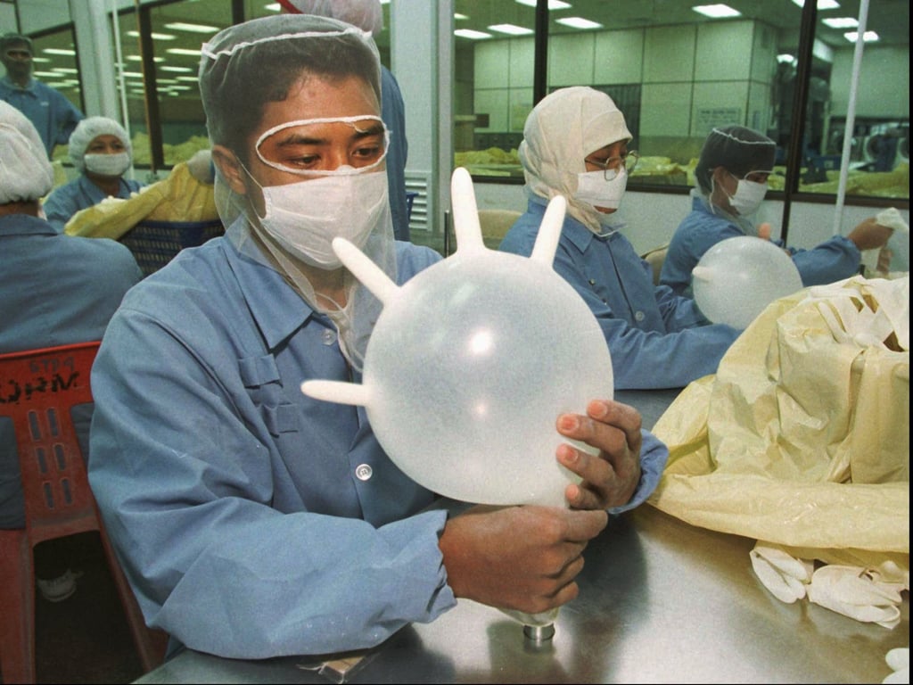 An employee uses compressed air to check for defects in latex gloves at a factory in Malaysia. Photo: AP An employee uses compressed air to check for defects in latex gloves at a factory in Malaysia. Photo: AP