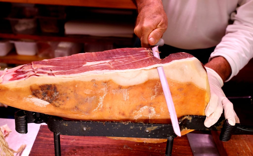 A grocer slices prosciutto ham in a deli. Photo: Reuters A grocer slices prosciutto ham in a deli. Photo: Reuters