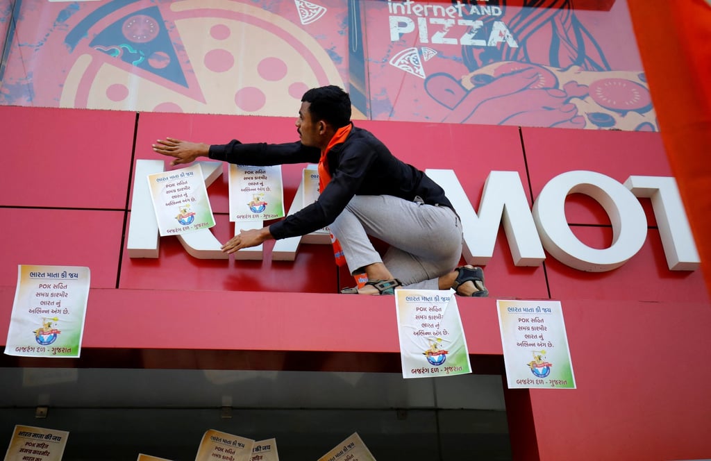 A Hindu activist covers the logo of KIA Motors during protests. Photo: Reuters
