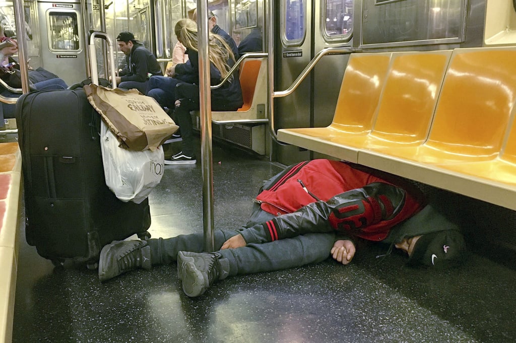 A man sleeps under the seats of a subway car in New York in October 2017. Photo: AP