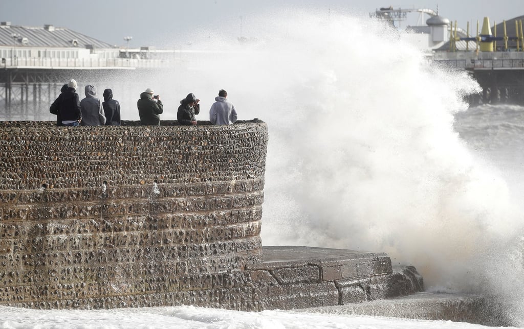 People take pictures as a storm surge breaks against the pier in Brighton, England on Friday. Photo: Reuters People take pictures as a storm surge breaks against the pier in Brighton, England on Friday. Photo: Reuters