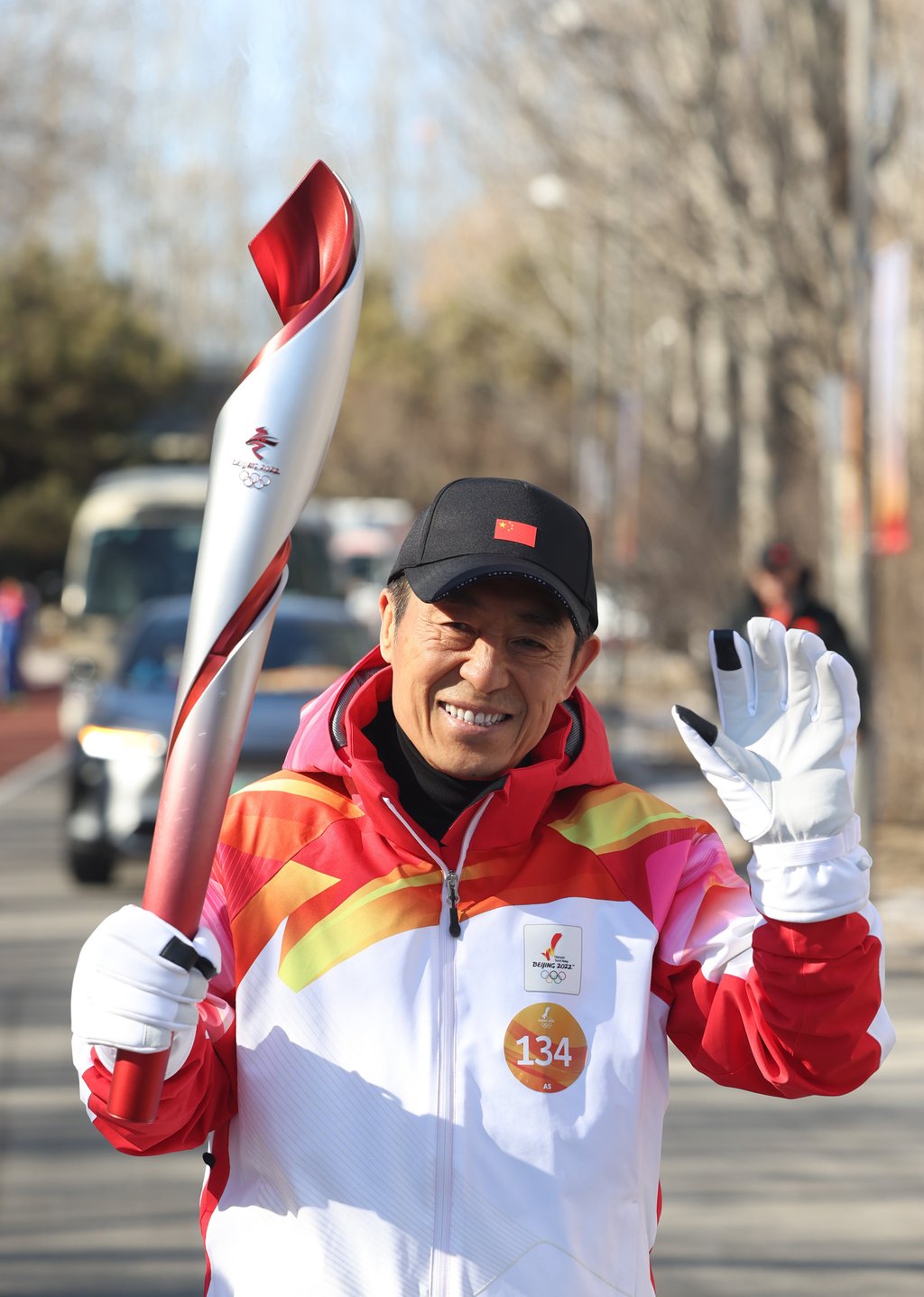 Zhang Yimou runs with the torch during the Beijing 2022 Olympic Torch Relay at the Olympic Forest Park. Photo: Xinhua/Jia Haocheng
