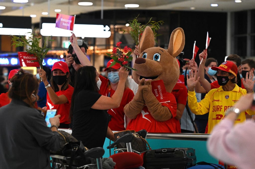 Staff offer flowers to passengers upon their arrival at Sydney International Airport. Photo: AFP