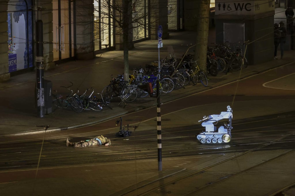 The suspect on the ground outside the Apple store, next to a police robot. Photo: EPA