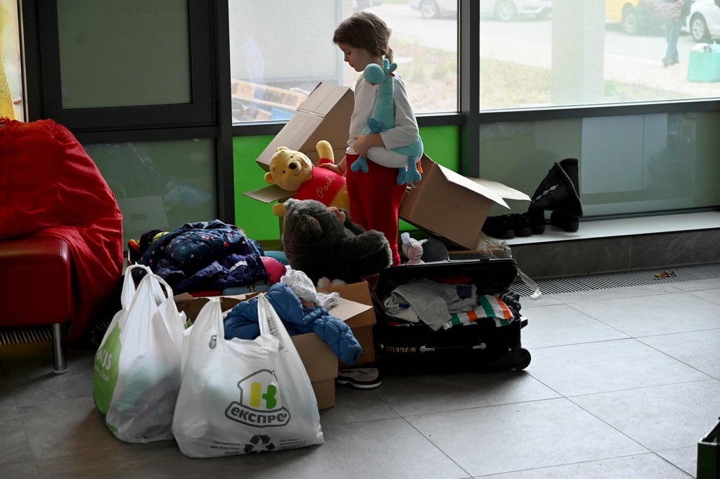 A Ukrainian child holds her toys as she stands with her family’s belongings awaiting evacuation. Photo: AFP