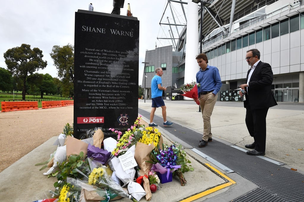 Victorian Minister for Sport and Major Events Martin Pakula (centre) places a tribute to cricketer Shane Warne outside the MCG in Melbourne. Photo: EPA-EFE