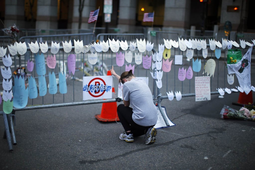 A woman kneels and cries in front of a memorial to the Boston Marathon bombings victims at the barricades surrounding the scene in April 2013. Photo: Reuters