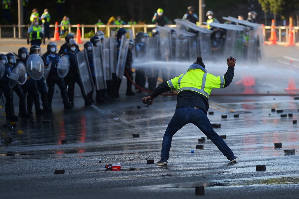A man faces off with police near New Zealand’s parliament as a protest against Covid-19 vaccine mandates and restrictions is cleared earlier this month. Photo: AFP via Getty Images/TNS A man faces off with police near New Zealand’s parliament as a protest against Covid-19 vaccine mandates and restrictions is cleared earlier this month. Photo: AFP via Getty Images/TNS
