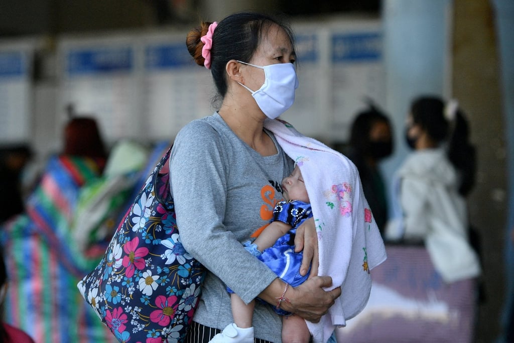 A woman carries her baby at a bus station in Bangkok. Photo: Reuters A woman carries her baby at a bus station in Bangkok. Photo: Reuters
