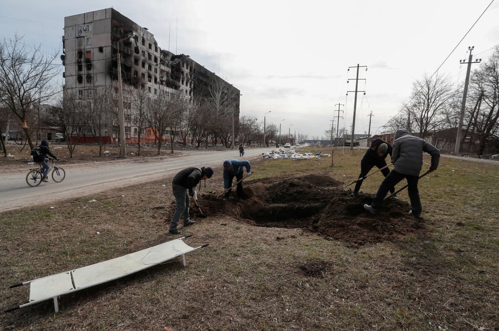 People dig a grave on Sunday for victims killed in the besieged southern port city of Mariupol, Ukraine. Photo: Reuters