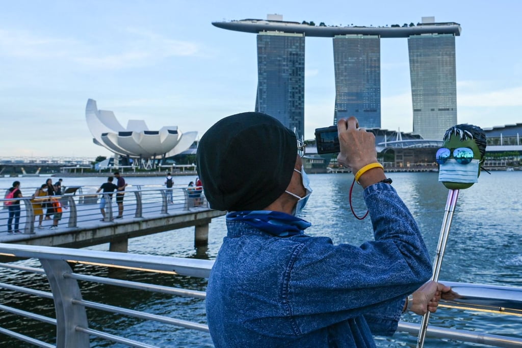A man takes pictures of a model wearing a face mask in front of the Marina Bay Sands hotel and resort in Singapore. Photo: AFP A man takes pictures of a model wearing a face mask in front of the Marina Bay Sands hotel and resort in Singapore. Photo: AFP
