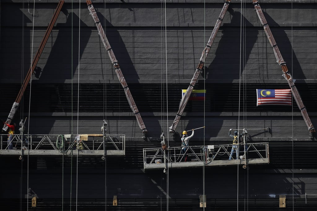 Construction workers paint a building in Kuala Lumpur. Photo: EPA-EFE