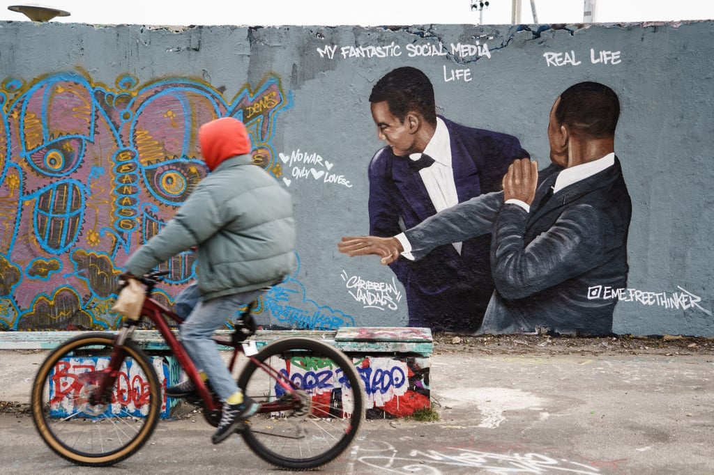 A cyclist on Friday passes a graffiti mural in a public park in Berlin, Germany that depicts the Will Smith’s viral Oscars slap. The artwork is by Dominican artist Jesus Cruz Artiles, aka Eme Freethinker. Photo: EPA-EFE