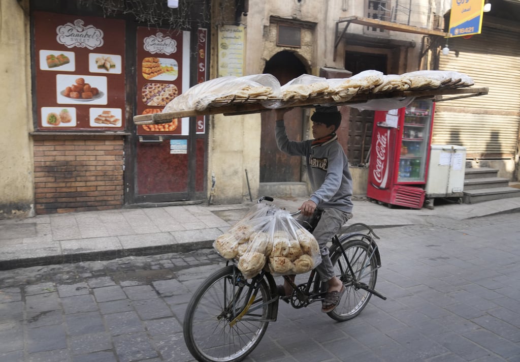 A vendor balances a tray of Egyptian “Baladi” flatbread as he cycles through Cairo’s old district on March 22. Photo: AP