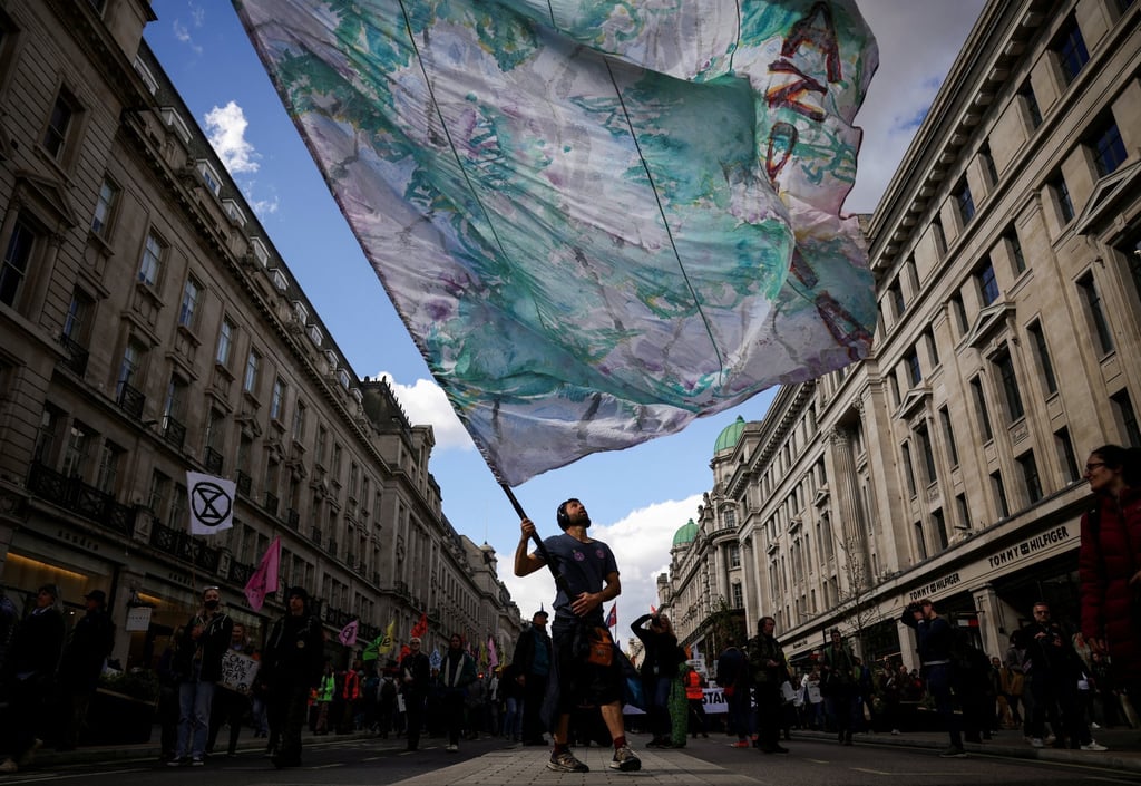 A man holds up a flag as climate activists from Extinction Rebellion take part in a demonstration at Oxford Circus in London, UK on April 9. Photo: Reuters