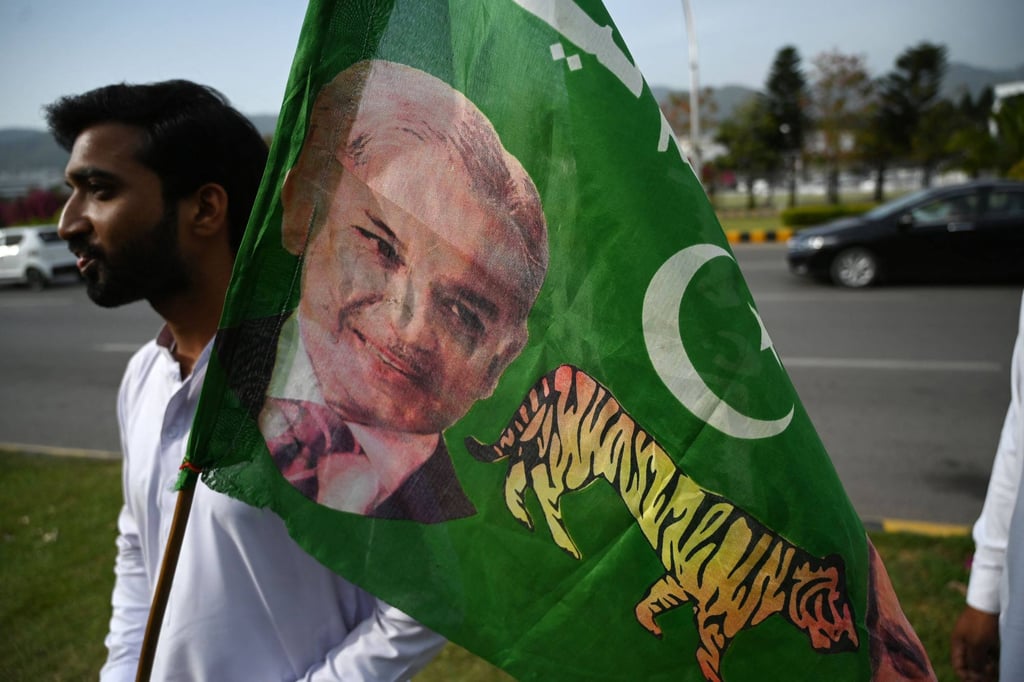 A supporter of Pakistan Muslim League-N holds a party flag with an image of Shehbaz Sharif outside the parliament house building in Islamabad on April 11, 2022. Photo: AFP