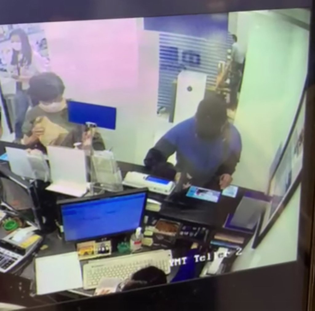 A screengrab showing the robber pointing the gun-like object at the bank teller. Photo: Handout A screengrab showing the robber pointing the gun-like object at the bank teller. Photo: Handout