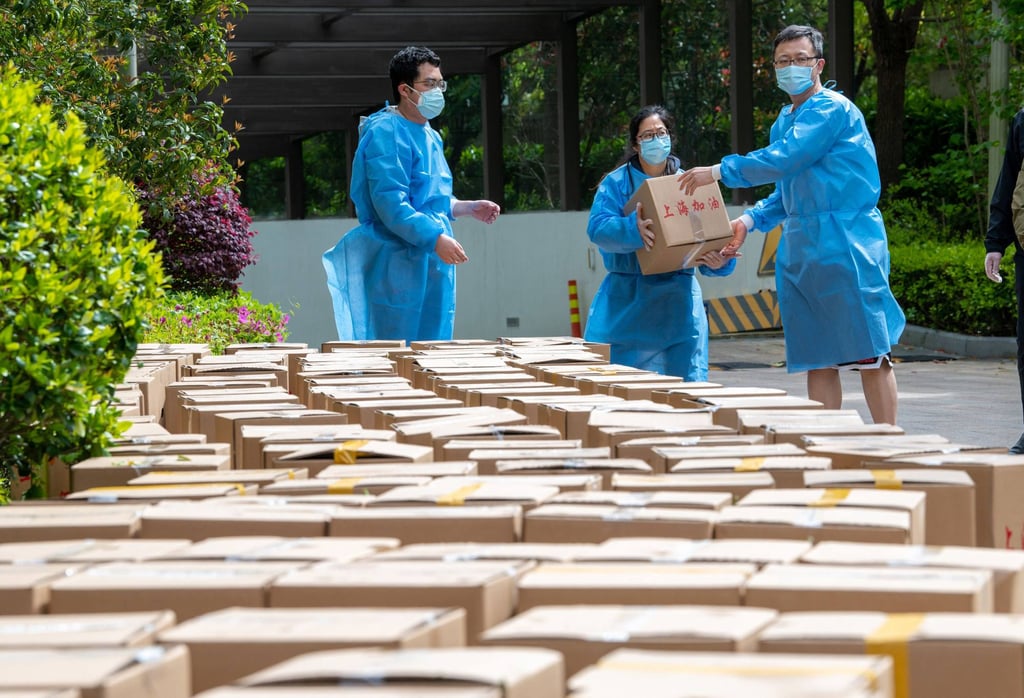Community volunteers deliver boxes of food which are distributed by local governament to residents in a compound during a Covid-19 lockdown, in Pudong district in Shanghai on April 15, 2022. Photo: Agence France-Presse/ China OUT