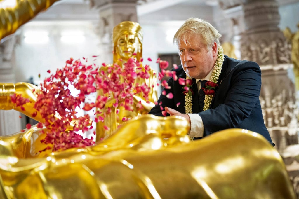 Britain’s Prime Minister Boris Johnson scatters rose petals during his visit at the Swaminarayan Akshardham temple in Gandhinagar. Photo: Pool/ AFP