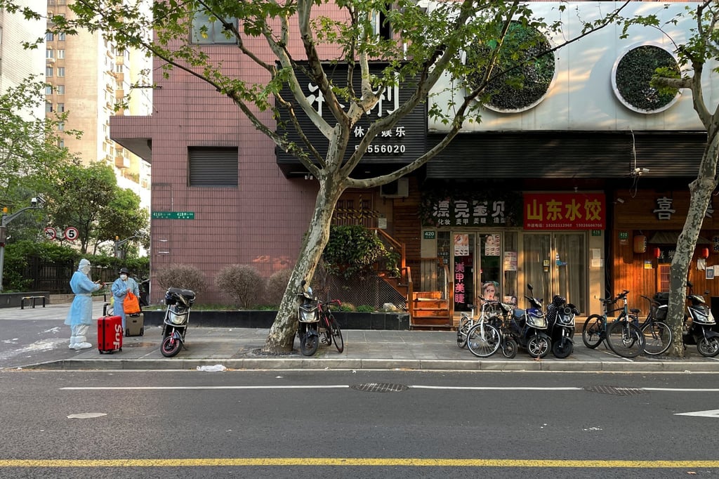 People in protective suits stand near closed stores on a street amid the coronavirus outbreak in Shanghai on April 21. Photo: Reuters People in protective suits stand near closed stores on a street amid the coronavirus outbreak in Shanghai on April 21. Photo: Reuters