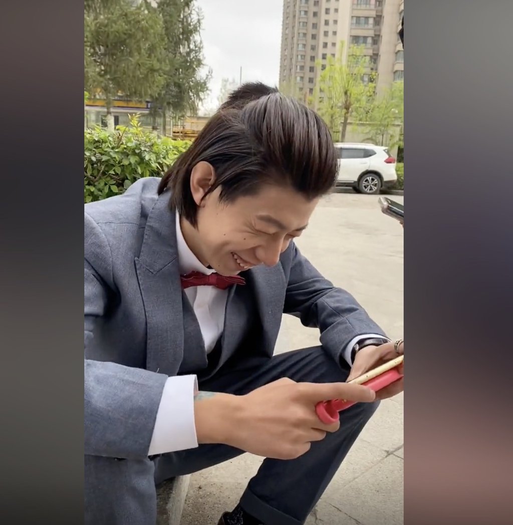 Deng laughs as he is filmed watching his own wedding outside the restaurant. Photo: Douyin
