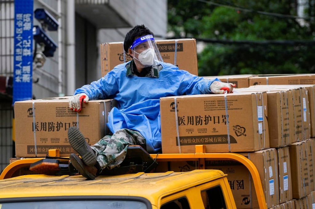 A worker in a protective suit sat on top of a truck transporting protective masks in Shanghai on April 28, 2022. Photo: Reuters