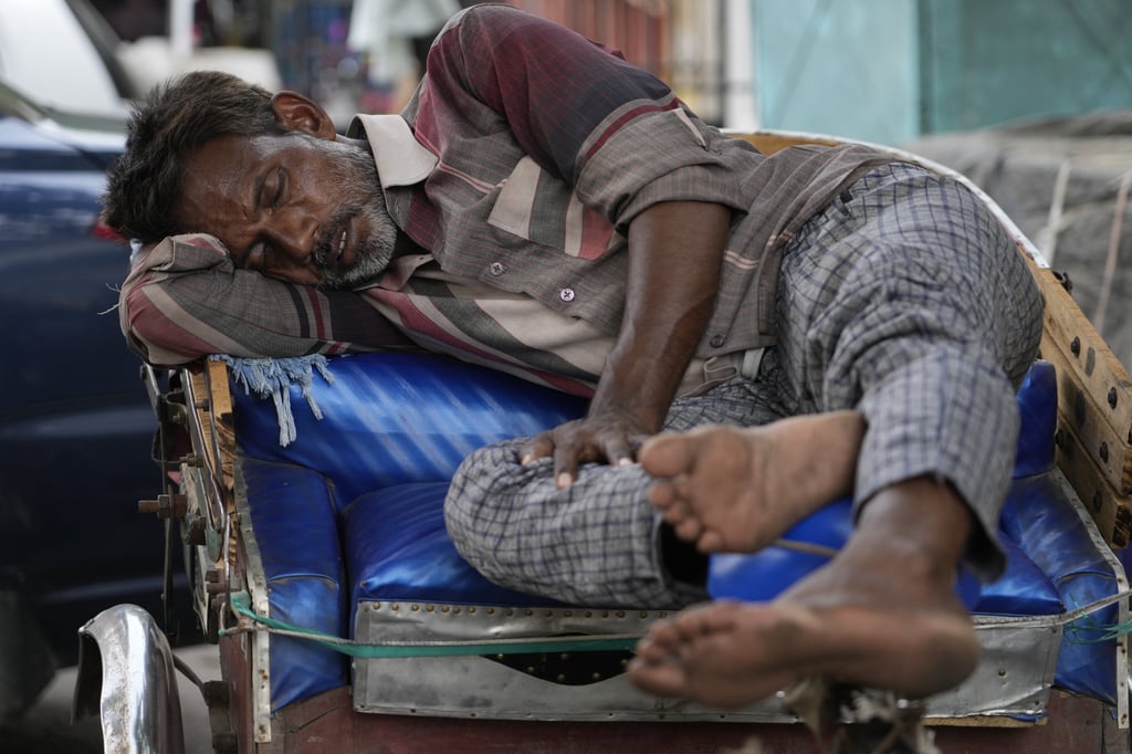A rickshaw driver sleeps on his vehicle in the shade amid the heatwave in Uttar Pradesh. Photo: AP